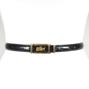 May include: Black belt with a gold-tone buckle featuring a carriage and horse design. The belt is made of a textured material, likely leather, and is worn around the waist. A classic accessory.