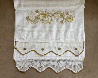 May include: White hand towel with gold floral embroidery and lace trim. The towel features a detailed floral design across the top and decorative lace along the bottom edge. The lace trim has a scalloped edge with gold accents.