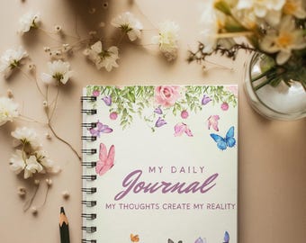 May include: A white journal with a floral design and butterflies. The cover reads "My Daily Journal My Thoughts Create My Reality".