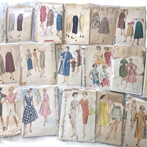 May include: A collection of vintage sewing patterns for dresses and skirts. The patterns are from Vogue, Simplicity, and McCall's. The patterns are in various colours, including red, blue, green, and yellow.