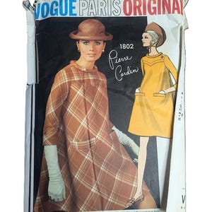 May include: Vintage Vogue Paris Original sewing pattern featuring a Pierre Cardin design. The cover shows a woman in a brown plaid coat and another in a yellow dress. The text includes "Vogue Paris Original" and "Pierre Cardin".