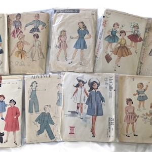 Puede incluir: Una colección de patrones de costura vintage para ropa de niños. Los patrones presentan varios estilos de vestidos, faldas, pantalones y abrigos. Los patrones están impresos en papel y tienen ilustraciones de las prendas terminadas.