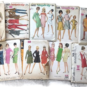 May include: A collection of vintage sewing patterns for dresses. The patterns are printed on paper and feature illustrations of women wearing the dresses. The patterns are from the 1960s and include brands like Simplicity and Butterick.