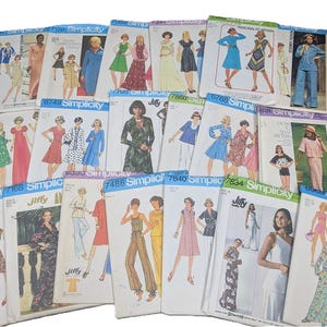 May include: A collection of vintage Simplicity and Jiffy sewing patterns. The patterns feature illustrations of various dresses, jumpsuits, and separates in a range of colors. The patterns are from the 1970s and 1980s.