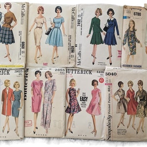 May include: A collection of vintage sewing patterns for dresses. The patterns are from the 1960s and feature a variety of styles, including A-line dresses, shift dresses, and dresses with collars. The patterns are in various colors, including pink, blue, green, and white.