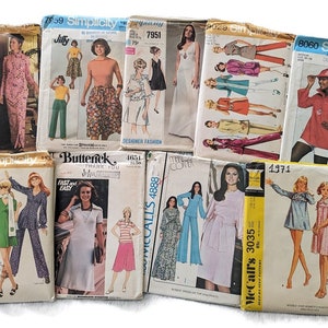 May include: A collection of vintage sewing patterns featuring various designs for dresses, tops, and pants. The patterns are from different brands, including Simplicity, Butterick, and McCall's. The patterns are in various colors, including pink, blue, green, and yellow.