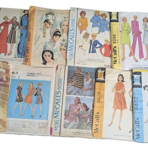 Puede incluir: Una colección de patrones de costura vintage para ropa, con varios diseños y estilos. Los patrones están impresos en papel e incluyen instrucciones y diagramas para crear prendas. Los patrones son de McCall's e incluyen números como 5293, 5039, 5159, 8826, 8402 y 4048.