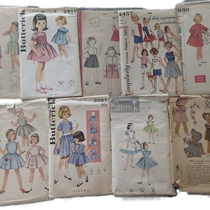 May include: A collection of vintage sewing patterns for children's clothing. The patterns feature illustrations of girls in dresses, skirts, and shorts. The patterns are from brands like Simplicity, Butterick, and McCall, and include prices like 25c and 50c.