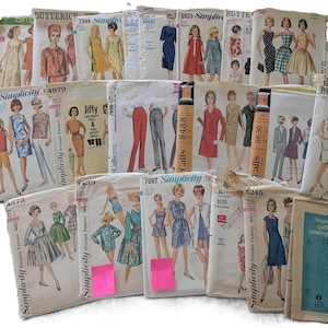 Op de afbeelding: Een verzameling vintage naaipatronen met verschillende ontwerpen voor jurken, rokken en pakken. De patronen zijn van merken als Simplicity en Butterick, met illustraties van de afgewerkte kledingstukken. Sommige patronen hebben prijskaartjes.