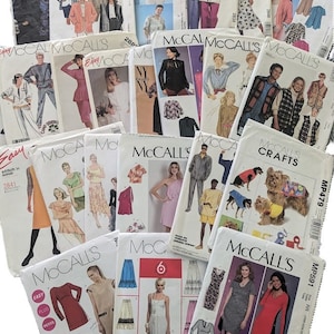 May include: A collection of vintage McCall's sewing pattern envelopes. The patterns feature various clothing designs for men and women, including dresses, jackets, and pants. The envelopes display images of the finished garments and include the McCall's logo.