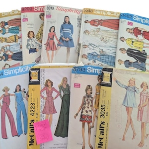 May include: A collection of vintage sewing patterns featuring illustrations of dresses, jumpsuits, and other garments. The patterns are from brands like Simplicity and McCall's, with various designs and styles from the mid-20th century.