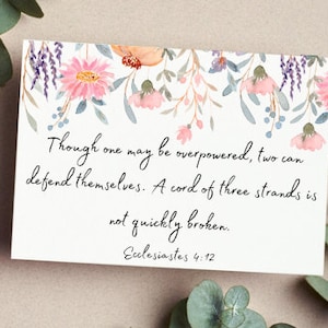 Puede incluir: Una tarjeta con un diseño floral de acuarela con la cita "Aunque uno pueda ser superado, dos pueden defenderse. Una cuerda de tres hilos no se rompe fácilmente. Eclesiastés 4:12"