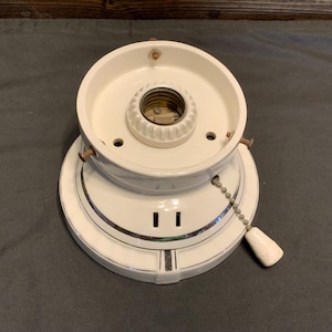 May include: White porcelain ceiling light fixture with a pull chain switch. The fixture has a decorative silver trim and two small holes on the side.