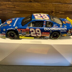 May include: A blue and white die-cast race car model with the number 29 prominently displayed. The car features sponsor logos, including Goodwrench Service, Goodyear, and Snap-on. The model is displayed on a white box.