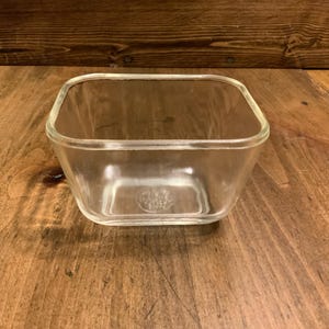 May include: A clear glass square baking dish with rounded edges.