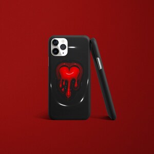 Op de afbeelding: Zwarte telefoonhoes met een rood druppelend hartontwerp. De hoes heeft een uitsparing voor de camera en een zwarte achtergrond.