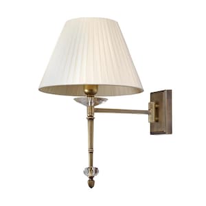 Könnte beinhalten: Eine Wandleuchte mit cremefarbenem, plissiertem Lampenschirm. Die Lampe hat einen messingfarbenen Metallrahmen mit Kristallakzenten. Das Design ist klassisch und elegant, geeignet für die Innenbeleuchtung.