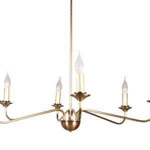 May include: A gold-coloured chandelier featuring six candle-style lights. The fixture has curved arms and a central decorative element. The bulbs are flame-shaped, and the design is elegant and classic.