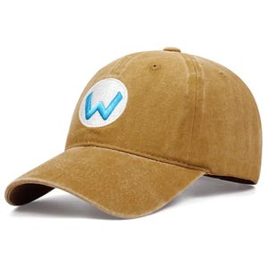 May include: A tan baseball cap with a curved brim. The cap features a white circular patch with a blue "W" embroidered on the front. The hat is made of a soft, worn material.