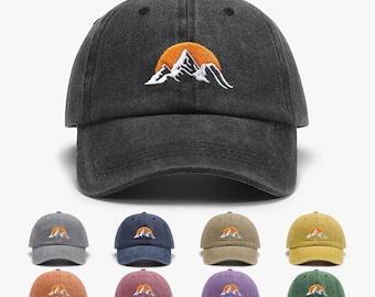 Könnte beinhalten: Dunkelgraue Baseballkappe mit einem gestickten Berg- und Sonnendesign. Die Kappe hat einen gebogenen Schirm und eine klassische Sechs-Panel-Konstruktion. Zusätzliche Kappen in verschiedenen Farben, darunter Grau, Blau und Grün, werden unten angezeigt.