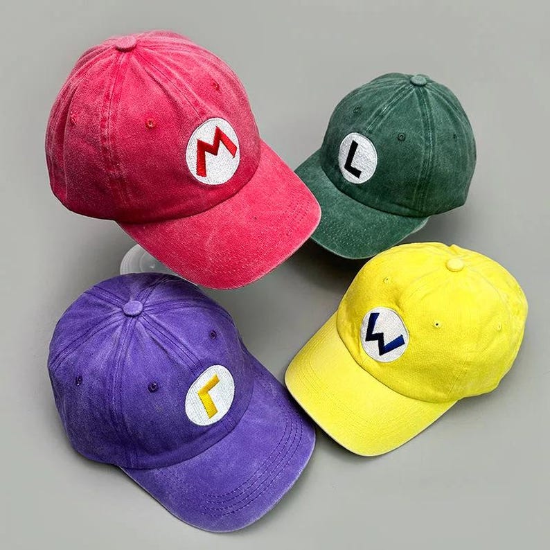 May include: Four colorful baseball caps. A red cap with a white "M", a green cap with a white "L", a purple cap with a white "&Gamma;", and a yellow cap with a white "W". All caps have a distressed, vintage look.