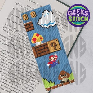May include: A blue and brown pixel art bookmark featuring a character from the Super Mario Bros. video game. The bookmark shows Mario jumping over a question block and a mushroom, with a ghost floating in the sky above.