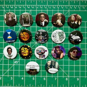 May include: A selection of circular pin badges with diverse designs. Some badges showcase portraits, while others display graphics such as a pizza slice, an hourglass, and text that reads "AMP HERE & THEP". Other badges have text that reads "I can act rather silly at times" and "I feel so sigma".