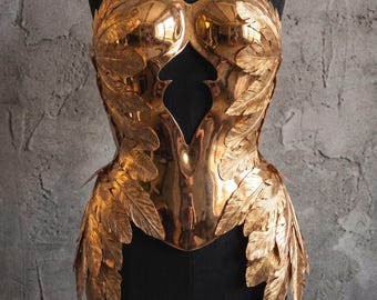 Peut inclure: Un haut corset sans bretelles en métal poli couleur cuivre, doté d'un corsage structuré avec une découpe centrale et une superposition complexe de motifs de plumes métalliques qui s'étendent de la poitrine jusqu'à la taille.