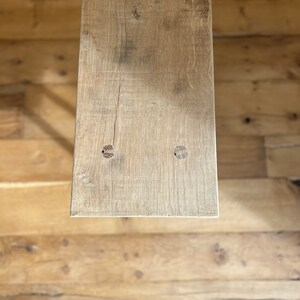 May include: A close-up of a light brown wooden plank with two knots. The plank is weathered and has a rustic appearance.