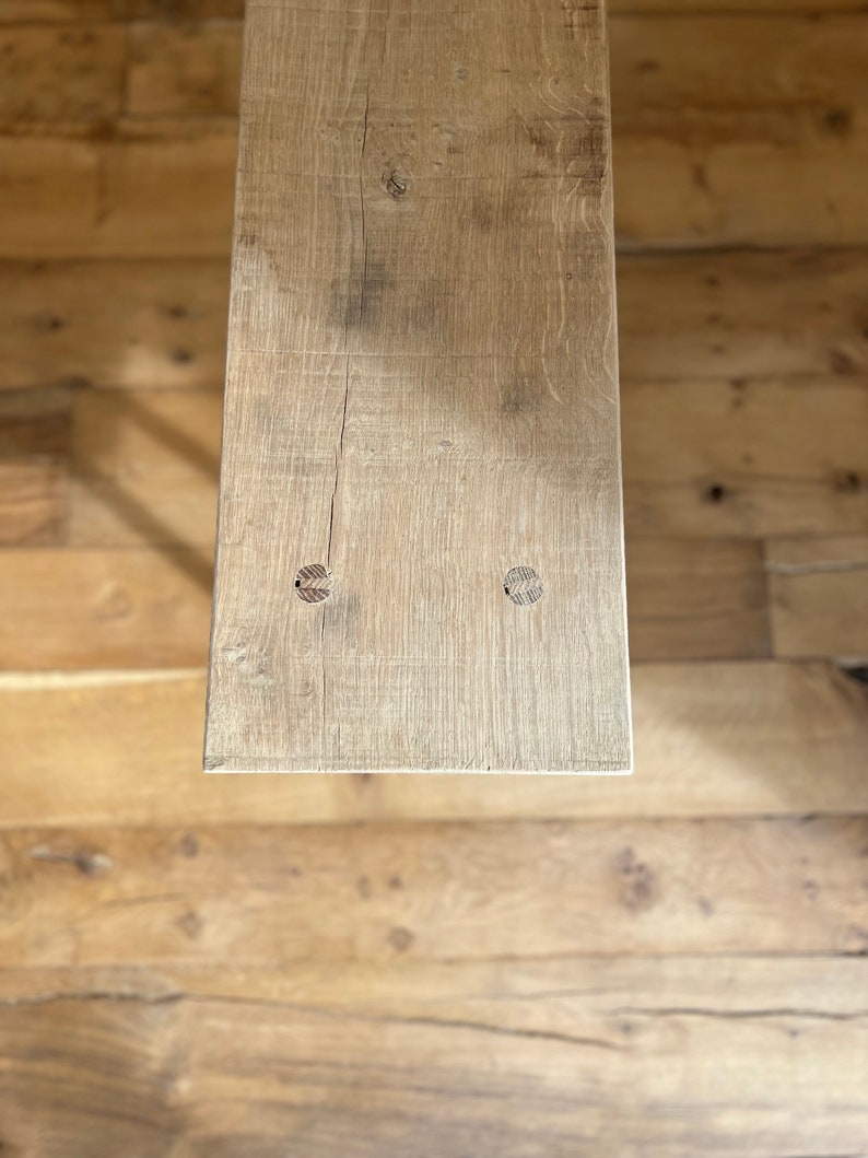 May include: A close-up of a light brown wooden plank with two knots. The plank is weathered and has a rustic appearance.