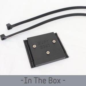 May include: A black rectangular device with the text "Eufy S340" and three screws, accompanied by two black cable ties. The items are on a white surface. The phrase "- In The Box -" is at the bottom.