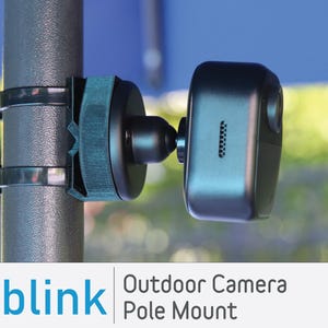 May include: A black Blink Outdoor Camera mounted on a pole using a black pole mount. The camera is pointed downwards and has a black and white design.