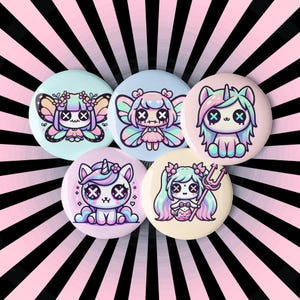May include: Five pastel-coloured button badges featuring cute cartoon characters. The badges depict a unicorn, a fairy, a mermaid, and two other characters with X's for eyes.