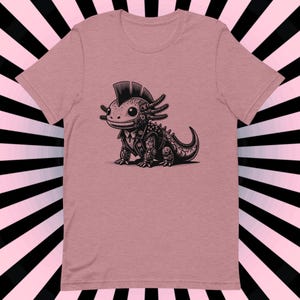 K&ouml;nnte beinhalten: Ein pinkfarbenes T-Shirt mit einer schwarz-wei&szlig;en Illustration eines Punk-Axolotl, das eine Lederjacke tr&auml;gt. Das Axolotl hat einen Irokesenschnitt und tr&auml;gt ein Nietenhalsband.
