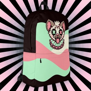 May include: A black backpack with a pink, green, and white design. The design features a cartoon hyena with X's for eyes and a tongue sticking out.