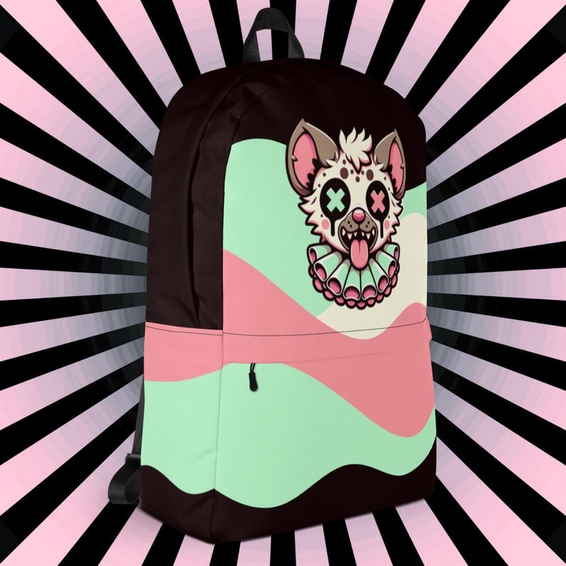 May include: A black backpack with a pink, green, and white design. The design features a cartoon hyena with X's for eyes and a tongue sticking out.