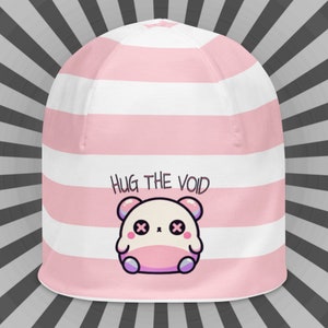 May include: Pink and white striped beanie with a cute cartoon character and the text "HUG THE VOID".