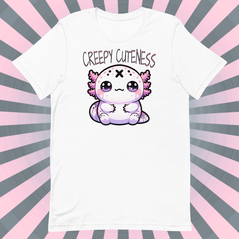Op de afbeelding: Wit T-shirt met een roze en witte axolotl-illustratie en de tekst "Creepy Cuteness" gedrukt op de voorkant.