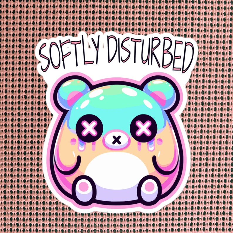 Może przedstawiać: Naklejka przedstawiająca kresk&oacute;wkowego niedźwiedzia z ciałem w pastelowych kolorach niebieskim i zielonym, r&oacute;żowymi uszami i białym futrem. Niedźwiedź ma duże oczy z czarnymi X i r&oacute;żowy nos. Naklejka ma r&oacute;żową ramkę i napis "SOFTLY DISTURBED" w kolorze czarnym.