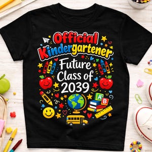 Peut inclure: T-shirt noir avec un motif graphique coloré pour la maternelle. Le motif comprend le texte "Official Kindergartener Future Class of 2039" avec des illustrations sur le thème de l'école.