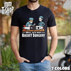 May include: A black t-shirt with a graphic of two cartoon surgeons working on a rocket with the text "Hey, it's not rocket surgery".