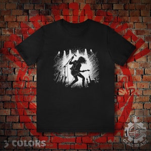 Puede incluir: Camiseta negra con una silueta blanca de un músico de rock actuando en un escenario con un micrófono y una guitarra. El músico está rodeado de una multitud de personas.
