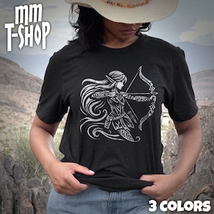 May include: A black t-shirt with a white graphic of an elf archer with a bow and arrow. The graphic is stylized and has a tribal design. The t-shirt is being worn by a person with a cowboy hat. The text "3 COLORS" is visible at the bottom of the image.