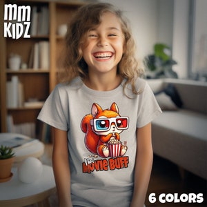 Puede incluir: Una camiseta gris con una ardilla de dibujos animados que lleva gafas 3D y come palomitas. El texto "Mini Movie Buff" está impreso en la camiseta.
