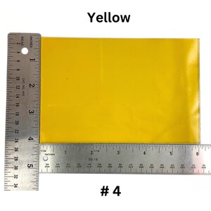 May include: A bright yellow square piece of paper, measuring approximately 4 inches by 6 inches, is shown next to a ruler. The paper is labeled "#4".