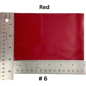 May include: A close-up of a red, rectangular piece of leather with a ruler measuring 6 inches in length. The leather is smooth and has a slight sheen. The ruler is marked with inches and picas. The text "#6" is printed below the ruler.