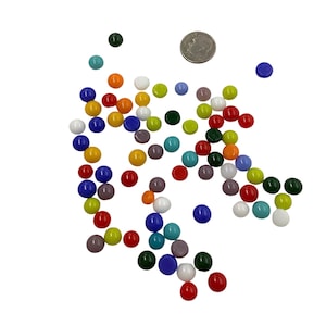 May include: A collection of colorful, round glass marbles in various colors, including red, blue, green, yellow, and white. A dime is included for size reference. The marbles are scattered on a white surface.