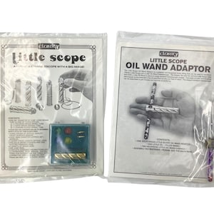 May include: Two sealed plastic packages of "Little Scope" products. One package features the text "Little Scope" and the phrase "Scope with a Big Image". The other package is labeled "Little Scope Oil Wand Adaptor". Both packages contain small brass and glass components.