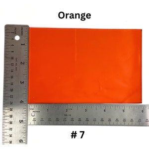May include: A bright orange square of material, measuring approximately 6 inches by 4 inches, with a ruler on either side. The material is labeled "#7".
