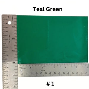 May include: Teal green vinyl sheet with a ruler for size reference. The sheet is approximately 6 inches by 4 inches. #1